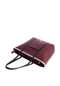 Bolso tote rectangular de cuero color burdeos con asas negras, ribete beige, bolsillo frontal y logotipo dorado sobre fondo blanco.