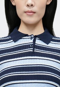 Μπλε ναυτικό και ανοιχτό μπλε ριγέ πόλο πουκάμισο με ραβδωτή υφή, με κούμπωμα με κουμπιά και μαλακό γιακά.