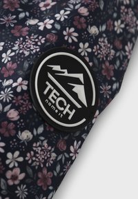 Lillemustriga seljakott tumesinise taustaga; omab reljeefset musta logot mägedega ja valgete tähtedega "TECH".