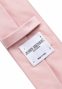 Ljusrosa randig slips med en texturerad yta, med en vit etikett där det står "JOHN HENRIC" och "Tillverkad i Italien" tryckt i svart.
