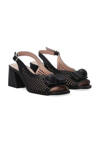 Schwarze, durchlöcherte Leder-Slingback-Schuhe mit einem kräftigen Absatz, offener Zehenpartie und dekorativen Akzenten, die ein rundes und quadratisches Element an der Vorderseite umfassen.