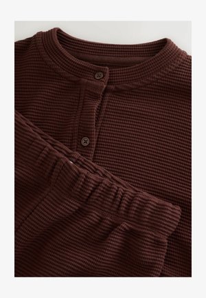 Brunt loungewear-set i våffelstickat tyg med långärmad topp med knappar och matchande byxor med resår i midjan.