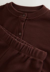 Brązowy zestaw do noszenia w domu z dzianiny w stylu waflowym, składający się z bluzki na długi rękaw z guzikami oraz pasujących spodni z elastycznym pasem.