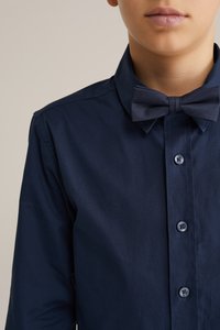 Tamsiai mėlynas mygtukų marškiniai su peteliške, su klasikiniu apykakle ir lygiu tekstūru. Į komplektą įeina paprasti tamsūs mygtukai priekyje.