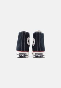 Μαύρα ψηλά καμβά παπούτσια με λευκές ραφές και λάστιχο σόλα. Διαθέτουν εμβληματικά μπαλώματα με λογότυπο αστέρι στη εξωτερική φτέρνα. Κλασικός σχεδιασμός.