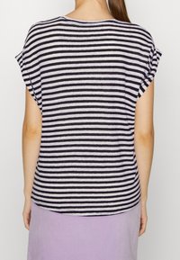 Pruhované tričko v černé a bílé barvě s krátkými rukávy, kulatým výstřihem a volným střihem. Tkanina vypadá měkce a lehce.