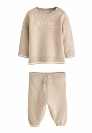 Beige strikket babyoutfit med langærmet top med knapper på skulderen og matchende bukser med snøre.