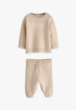 Beige strikket babyoutfit med langærmet top med knapper på skulderen og matchende bukser med snøre.