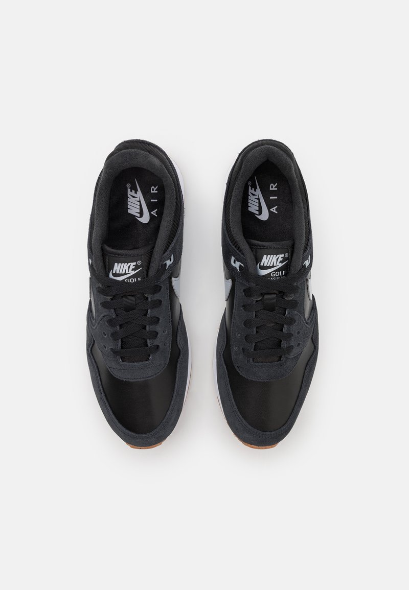 Black Nike sneakers with a mix of smooth and textured materials, featuring a rounded toe, flat laces, and a rubber sole with a visible logo.