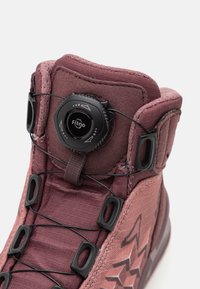 Scarpa alta con tomaia in tessuto color rosa polveroso, dotata di un quadrante nero tondo per la regolazione dei lacci e occhielli rinforzati. Accenti texture visibili.