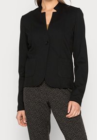 Blazer noir ajusté avec un col haut, fermeture à un bouton et deux poches avant. Matériau doux avec une texture lisse.