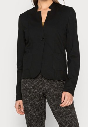 Blazer noir ajusté avec un col haut, fermeture à un bouton et deux poches avant. Matériau doux avec une texture lisse.