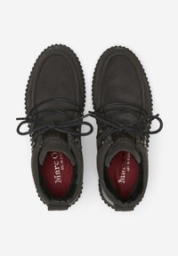 Stivaletti alla caviglia in suede marrone con lacci neri, suole in gomma e bordo texturizzato. All'interno presentano una fodera rossa con il nome del marchio impresso.