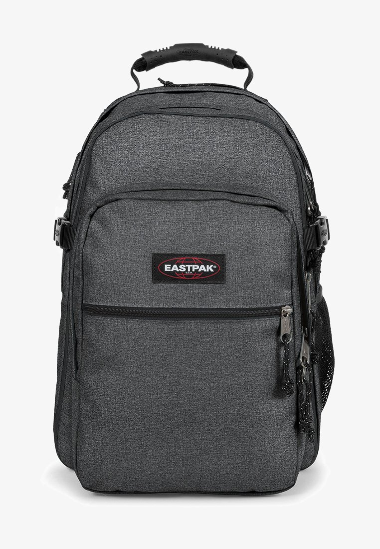 Mochila de tela gris con múltiples compartimentos, un bolsillo con cremallera en la parte frontal, bolsillo de malla lateral, asa reforzada y parche con logo. Cuenta con correas ajustables.