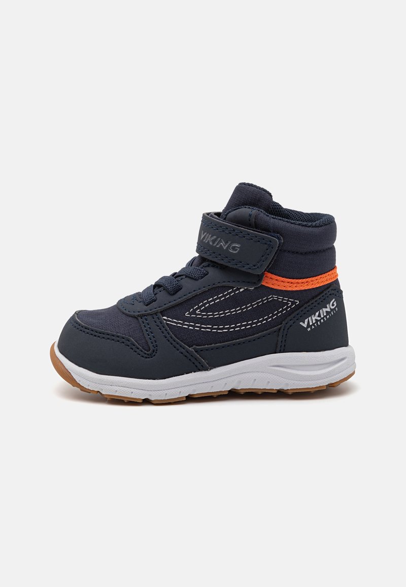 Navy blue children's sneakers with a padded collar, white sole, orange accent, and adjustable Velcro strap. Features stitching details and rubber outsole.