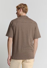 Korte mouwen bruine shirt met een geometrisch ruitpatroon in crème en oranje. Button-down kraag, lichte stof, relaxed fit.