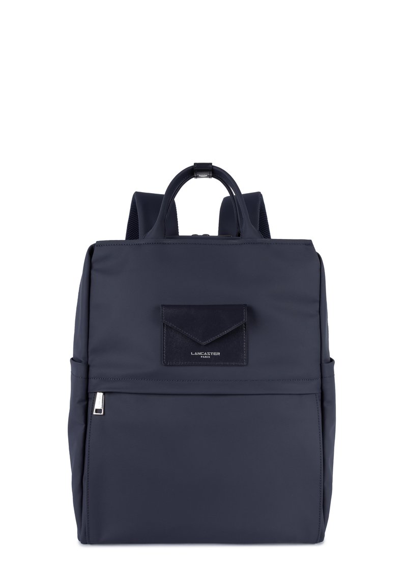 Sac à dos bleu marine avec poche zippée à l'avant, poignée supérieure, bretelles rembourrées et petite poche rectangulaire à rabat avec le logo Lancaster Paris.