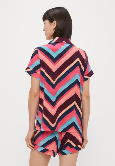 Kratki rukavi ružičastog i tamnoplavog pidžama seta s uzorkom u obliku cik-cak u plavoj, breskvastoj i tamnoplavoj boji; izrađen od mekog, laganog materijala.