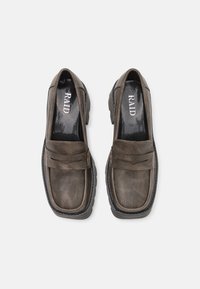 Pruun sünteetilisest nahast loafers madala kontsaga, millel on õmmeldud muster ja dekoratiivne riba ülevalt. Must sisetald.