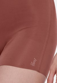 Bruine, rekbare shorts met een gladde textuur, voorzien van een klein logo op de zoom. De stof lijkt lichtgewicht en aansluitend te zijn.