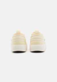 Sneaker color crema con una toma superiore liscia, colletto imbottito e suola intermedia bianca. Presenta una linguetta posteriore e il marchio "MOON BOOT".