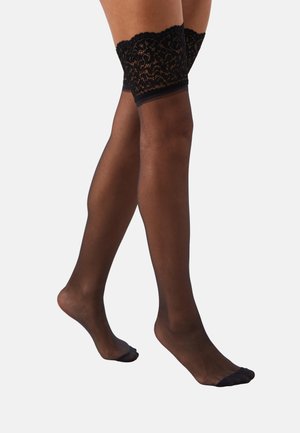 Chaussettes noires montantes avec une bande en dentelle en haut, corps transparent et bout renforcé. Texture lisse avec un motif floral en dentelle détaillé.
