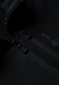 Schwarzer Neoprenanzugstoff mit glatter Textur, ausgestattet mit einem Reißverschluss und Branding. Enthält detaillierte Nähte und ein modernes Design.