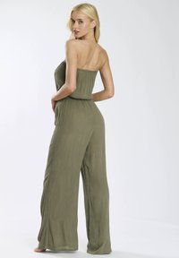 Jumpsuit sin mangas en verde oliva con un diseño texturizado, corte holgado y pantalones de pierna ancha, con una cinturilla elástica para mayor comodidad.