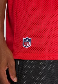 Piros NFL mez, lélegző hálós anyagból, apró lyukakkal. Fehér és kék hímzett NFL logóval rendelkezik az alján.