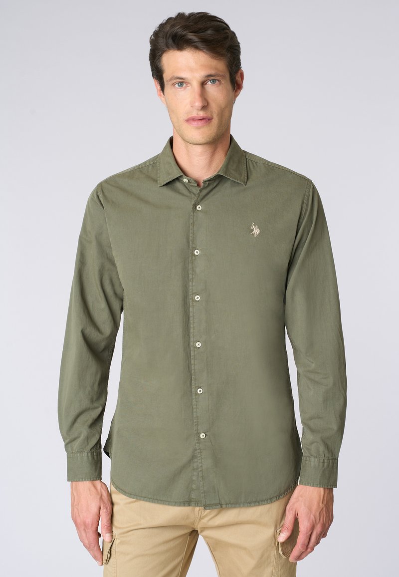 Camicia a maniche lunghe verde oliva con colletto button-down, dotata di bottoni frontali e di un piccolo emblema ricamato sul petto.