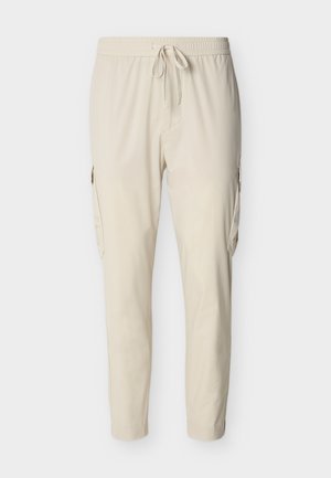 Μπεζ παντελόνια cargo με ελαστική μέση, κλείσιμο με κορδόνι, πλαϊνές τσέπες και κωνικά μπατζάκια, κατασκευασμένα από ελαφρύ, απαλό ύφασμα.