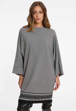 Robe à motif pied-de-poule en noir et blanc avec des manches larges, un col rond et une décoration en noir et blanc au niveau de l'ourlet.