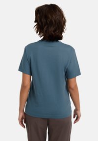 T-shirt in cotone teal a maniche corte con scollatura rotonda e vestibilità rilassata, mostrato da dietro, senza motivi o accessori distintivi.