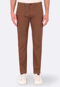 Pantaloni chino in cotone marrone, con una vestibilità slim, dotati di chiusura a bottone, tasche laterali e una texture liscia. Abbinati a sneaker bianche.