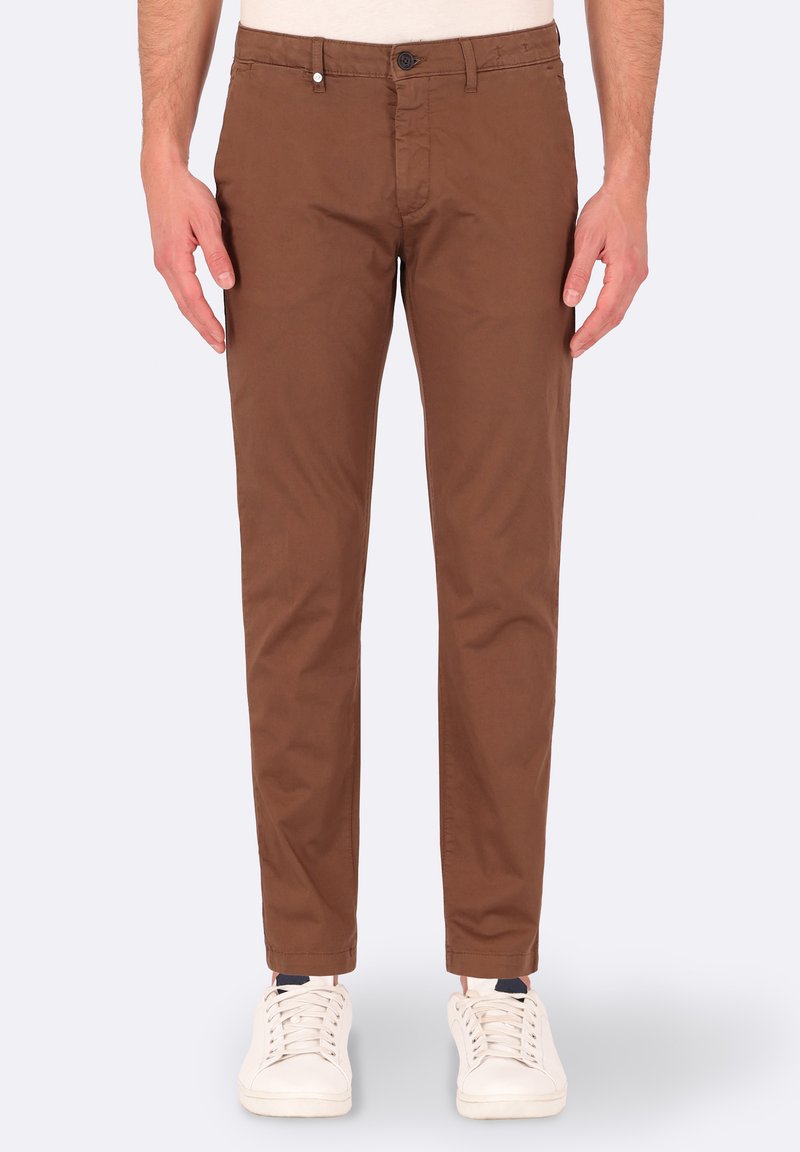 Pantaloni chino in cotone marrone, con una vestibilità slim, dotati di chiusura a bottone, tasche laterali e una texture liscia. Abbinati a sneaker bianche.