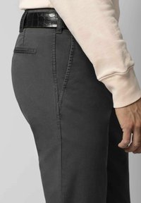 Dunkelgraue Hose aus glattem Stoff, im Slim-Fit-Stil mit geradem Bein und dezenten Seitentaschen. Ein schwarzer, strukturierter Gürtel ist sichtbar.