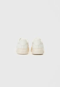 Weiße Leder-Sneakers mit einer strukturierten Gummisohle, die ein niedriges Profildesign und ein geprägtes Logo an der Ferse aufweisen.