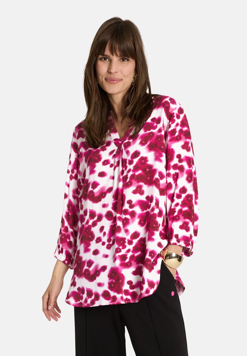 Leichte, langärmlige Bluse in Weiß mit einem abstrakten Muster in Pink und Burgunderrot. V-Ausschnitt-Design mit sichtbaren Details am Saum und an den Bündchen.