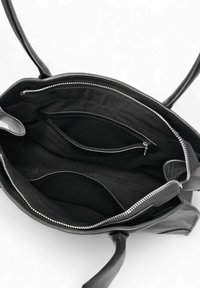 Sac à main en cuir noir ouvert pour montrer l'intérieur avec une poche zippée, des compartiments à glissière et une fermeture éclair argentée.