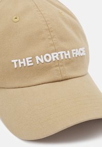 Boné caqui feito de algodão com uma aba arredondada. Apresenta texto bordado em branco "THE NORTH FACE" na frente, com detalhes em costura.