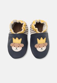Chaussures pour bébés en cuir bleu marine avec un motif de visage de chien et de couronne. Doublure en coton doux et finition en dentelle jaune. Motif rayé sur le dessus.