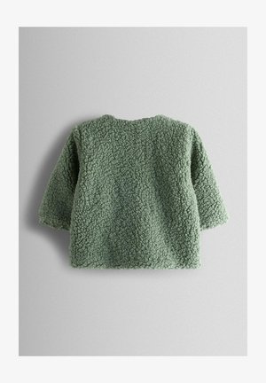 Pulover verde din fleece, cu suprafață moale și texturată, decolteu rotund și mâneci scurte, având o croială lejeră și fără închideri vizibile.