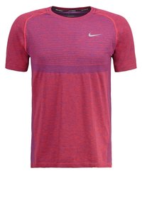 Camiseta atlética de Nike en rojo y púrpura, con mangas cortas, tela texturizada y un patrón de rayas contrastantes en el pecho. Logo de swoosh plata.