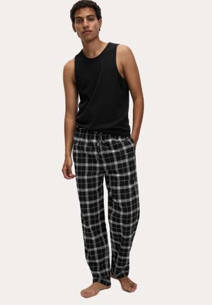 Schwarzes ärmelloses Tanktop kombiniert mit schwarz-weiß karierten Pyjamahosen. Der Stoff wirkt weich, die Hose hat einen elastischen Bund mit Kordelzug.