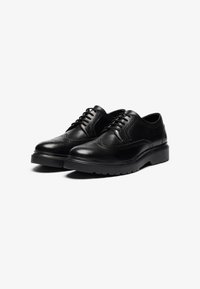Schwarze Lederdressschuhe mit runder Zehenform, Brogue-Details, glatter Oberfläche und einer dicken Gummisohle für besseren Halt. Standard Schnürverschluss.