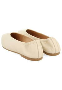 Ballerines en cuir beige clair avec un bout arrondi, une bordure élastique et une semelle plate lisse couleur tan.