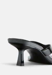 Mule en cuir verni noir avec bout carré et petit talon kitten évasé sur fond blanc uni.