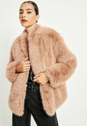 Faux pälsjacka i mjuk blekrosa med en bred krage och långa ärmar. Har en texturerad yta och avslappnad passform, tillsammans med svarta jeans.