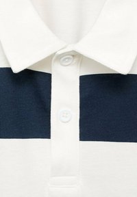 Polo con base bianca e righe orizzontali blu navy. Presenta un colletto classico e una chiusura a tre bottoni; realizzato in cotone testurizzato.