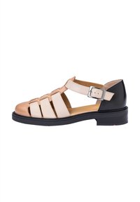Sandalia de tiras que presenta una combinación de cuero beige y crema, panel trasero negro, punta redonda, tacón bajo y cierre ajustable con hebilla.